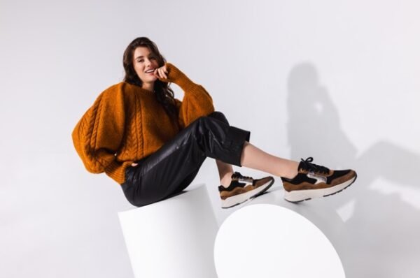 model met oranje trui en sneakers